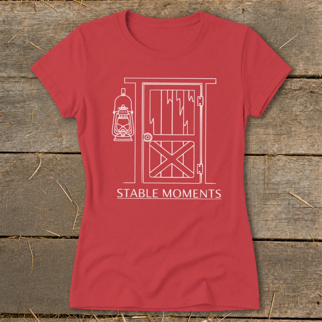 Red t-shirt with white line art of barn door, lantern, and text "STABLE MOMENTS".
