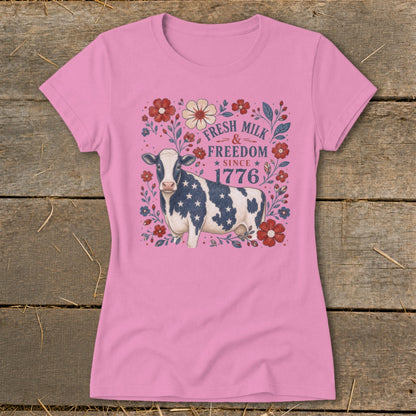 Pink t-shirt with a cow, flowers, and text: "FRESH MILK & FREEDOM SINCE 1776".