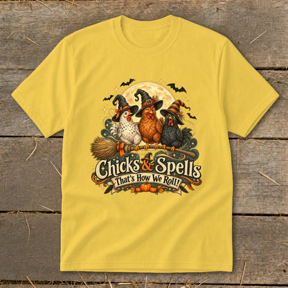 Yellow t-shirt with three chickens in witch hats flying on a broomstick with "Chicks & Spells" text.