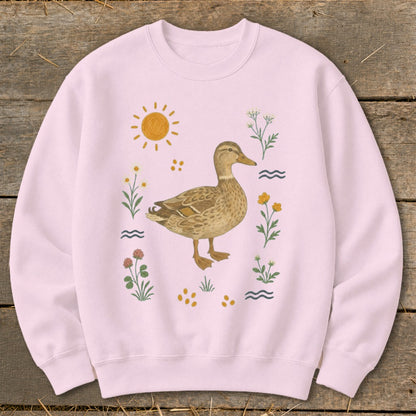 Pink sweatshirt with a watercolor illustration of a mallard duck surrounded by flowers and sun.