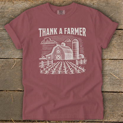 Maroon t-shirt with "Thank a Farmer" text and a farm scene illustration.