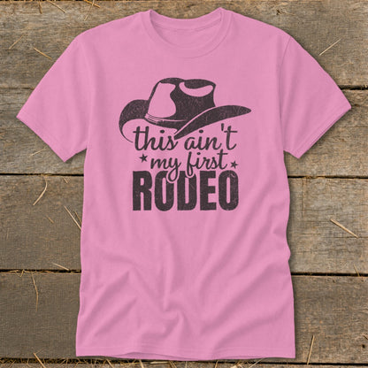 Pink t-shirt with cowboy hat graphic and text "this ain't *my first* RODEO"