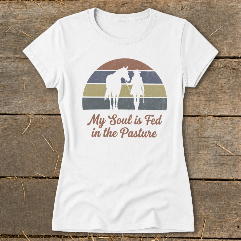 White t-shirt with horse and rider silhouette, vintage sunset, and text "My Soul is Fed in the Pasture".