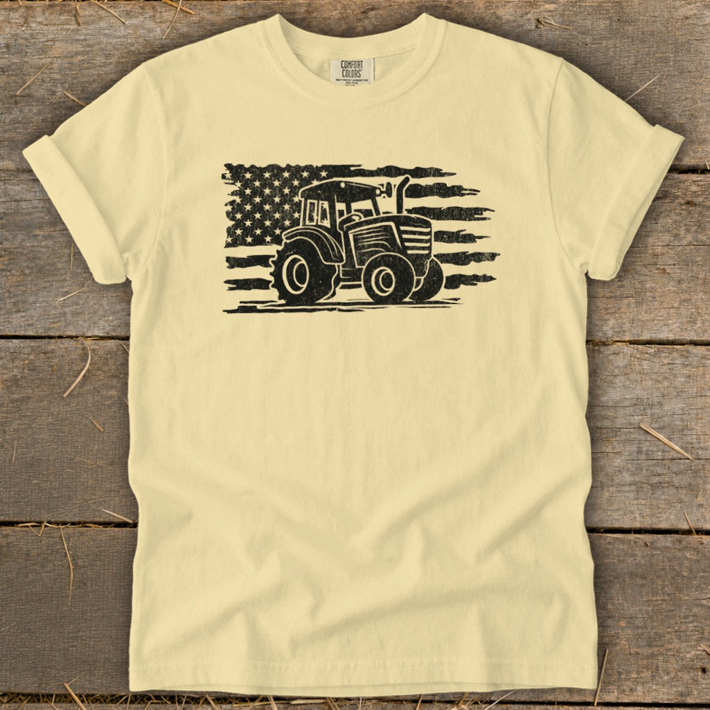Tractor silhouette with distressed American flag on a pale yellow t-shirt.