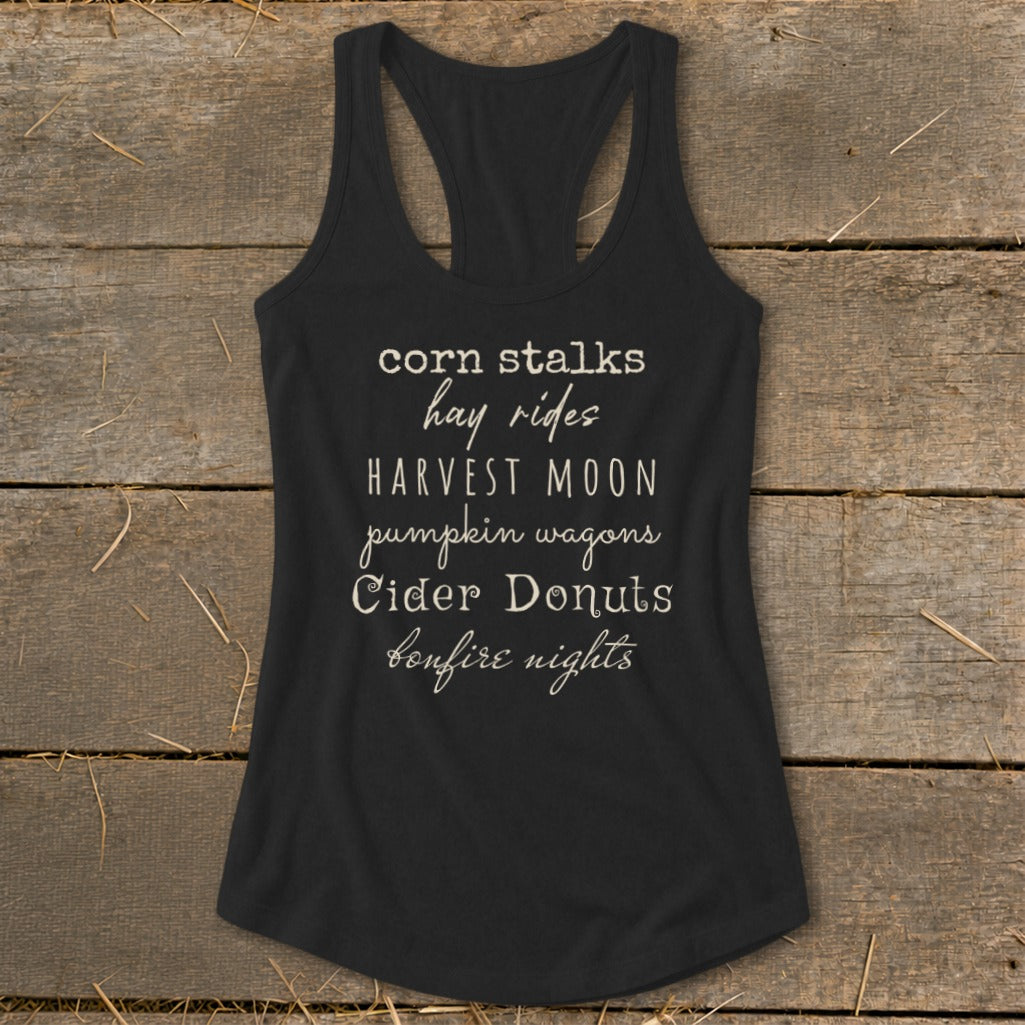 Black tank top with list of fall activities: corn stalks, hay rides, harvest moon, pumpkin wagons, cider donuts, bonfire nights.