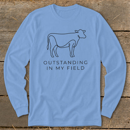 Light blue long-sleeve shirt with line drawing of a cow and text "OUTSTANDING IN MY FIELD".