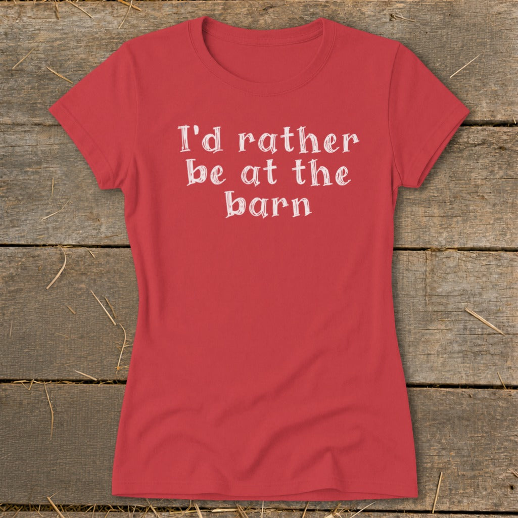 Red t-shirt with white text "I'd rather be at the barn" on wooden background.
