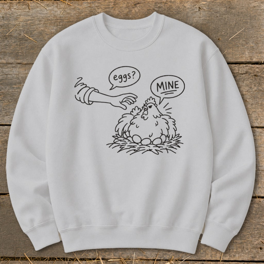 White crewneck sweatshirt with a line drawing of a chicken guarding its eggs, labeled "MINE".
