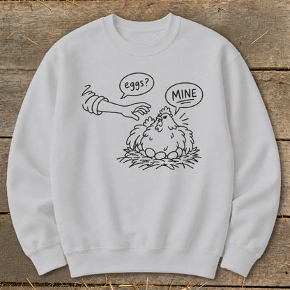 White crewneck sweatshirt with a line drawing of a chicken guarding its eggs, labeled "MINE".