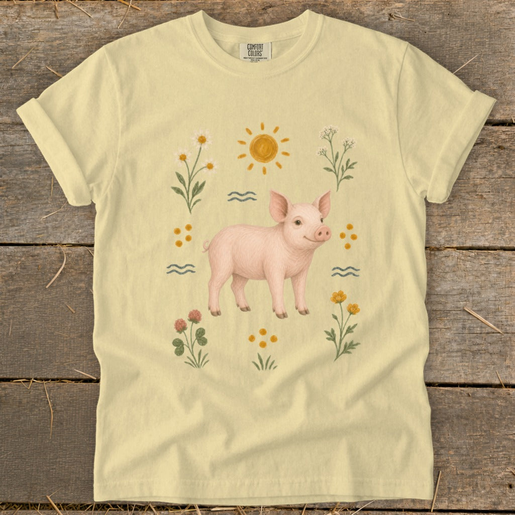 Yellow t-shirt with a pink piglet surrounded by flowers, sun, and waves.