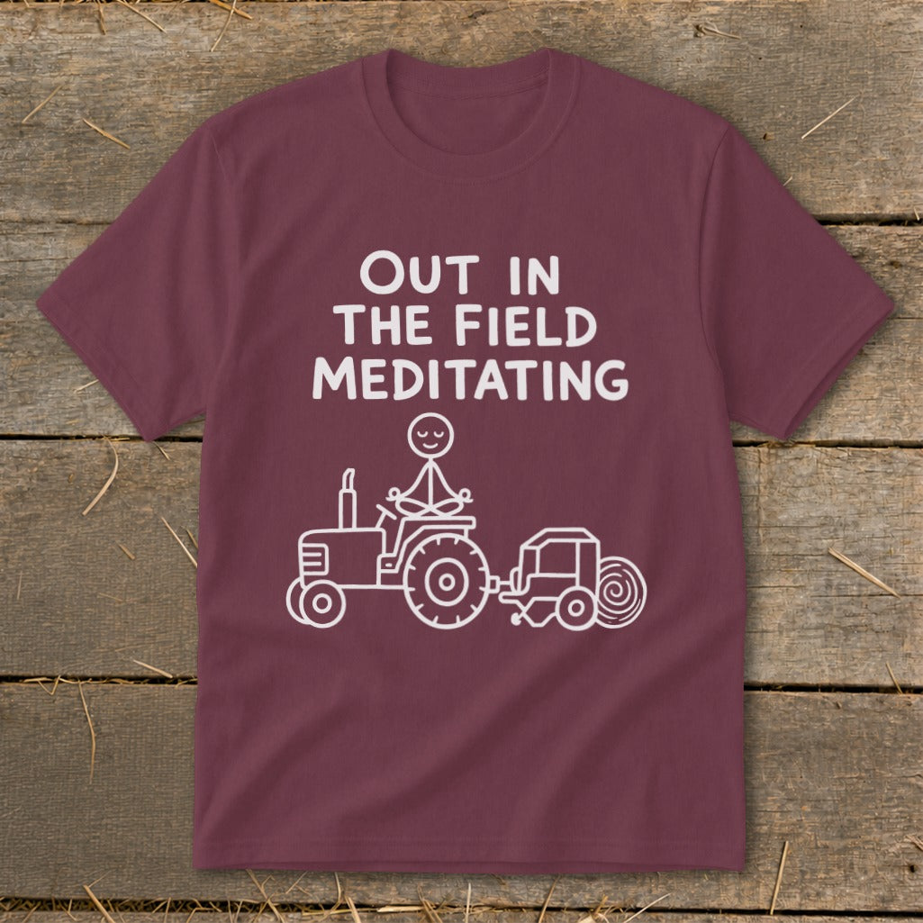 Maroon t-shirt with white text and graphic of stick figure meditating on tractor.
