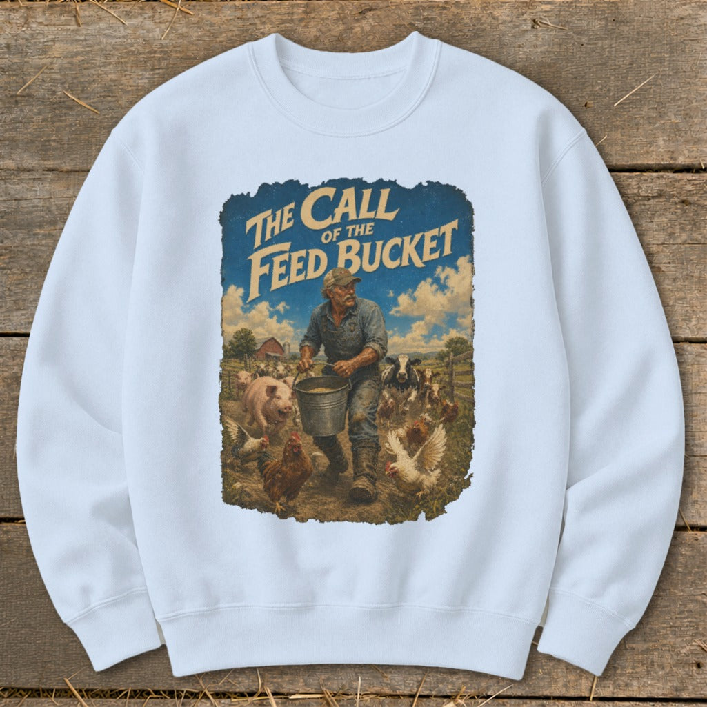 "The Call of the Feed Bucket" text graphic on a light blue sweatshirt with a farm scene.