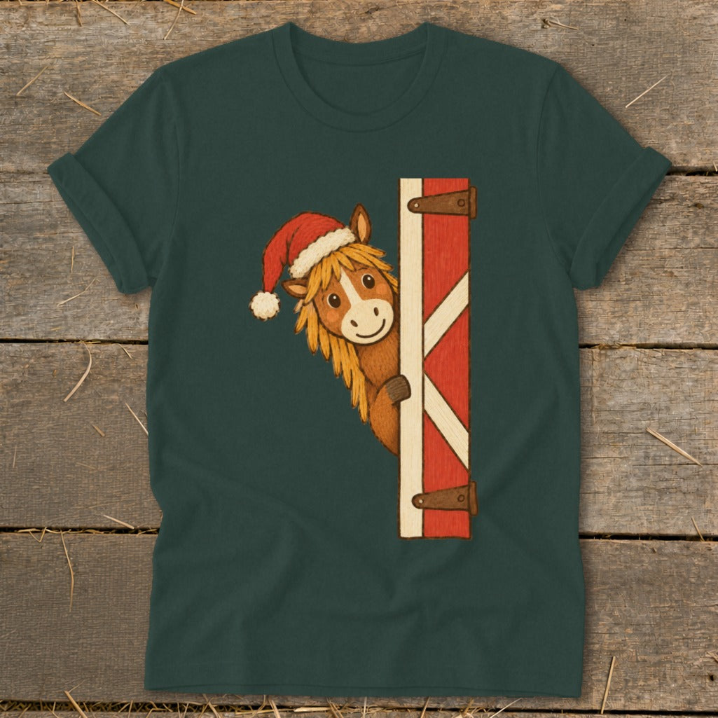 Horse wearing Santa hat peeks from behind barn door graphic on green t-shirt.