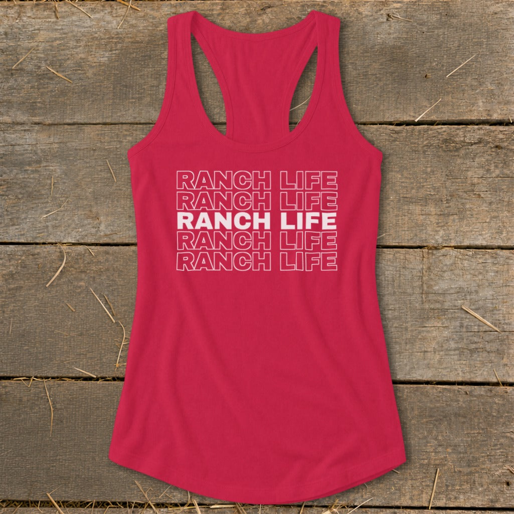 Red racerback tank top with white stacked text reading "RANCH LIFE" laid flat on weathered wood.
