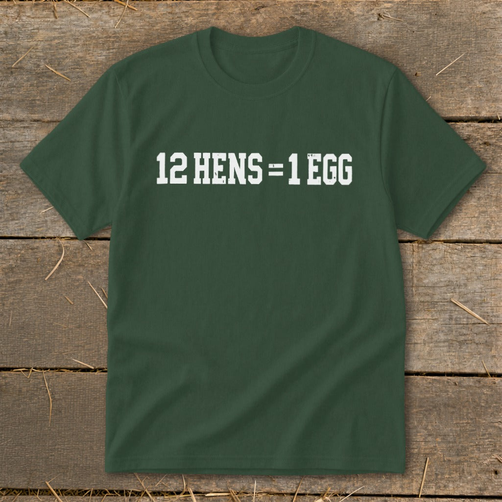 Dark green short-sleeve t-shirt with white block lettering that reads 12 HENS = 1 EGG laid flat on a rustic wooden background.