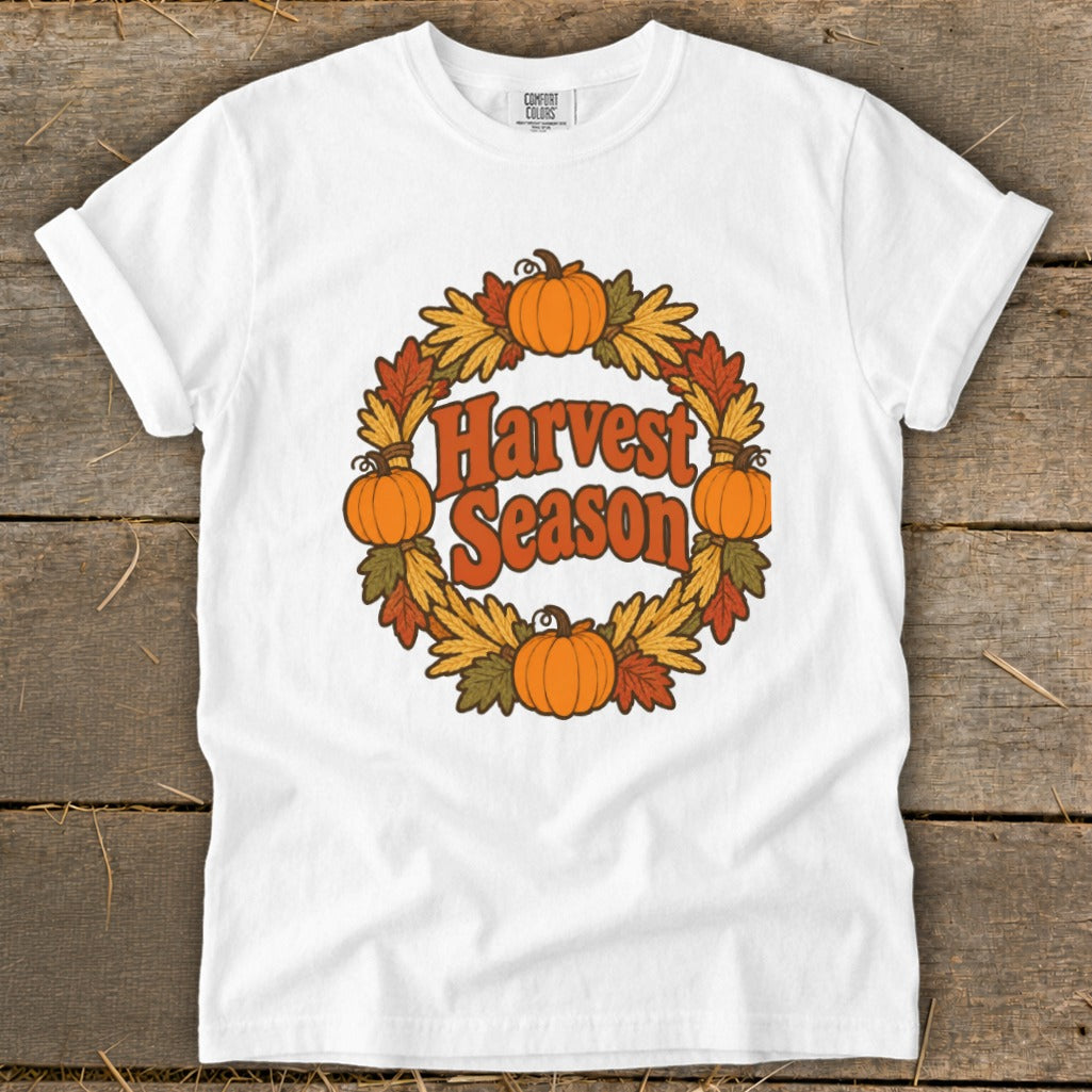 White t-shirt with orange text "Harvest Season" inside a wreath of pumpkins and fall leaves.