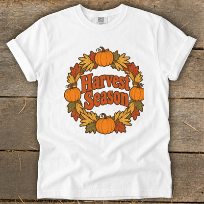 White t-shirt with orange text "Harvest Season" inside a wreath of pumpkins and fall leaves.