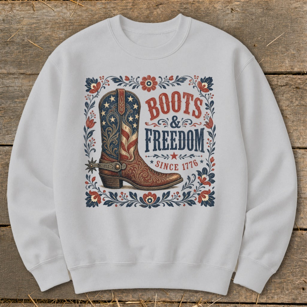 White crewneck sweatshirt with "Boots & Freedom Since 1776" text and American flag boot graphic.