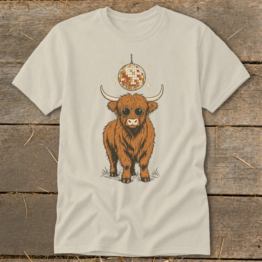 Highland cow with sunglasses and disco ball graphic on a tan t-shirt.