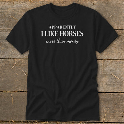 Black t-shirt with white text reading "APPARENTLY I LIKE HORSES more than money".