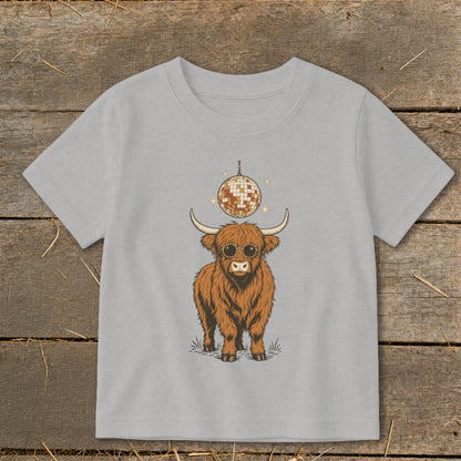 Highland cow wearing sunglasses under a disco ball on a light gray t-shirt.