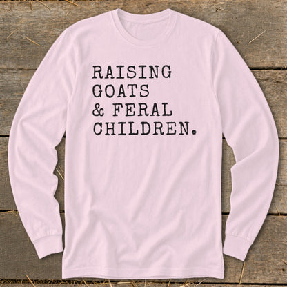 Pink long sleeve shirt with text "RAISING GOATS & FERAL CHILDREN."