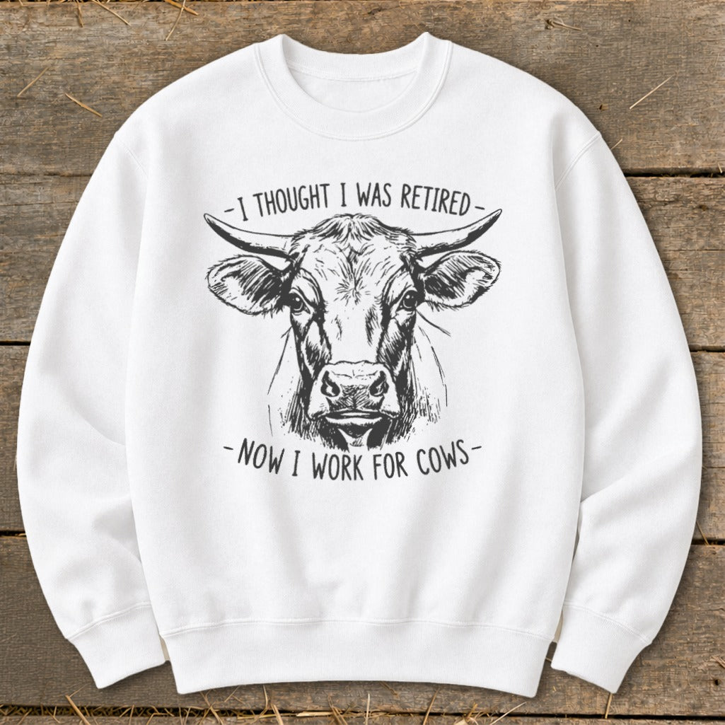 White sweatshirt with a black line drawing of a cow's head and the text "I thought I was retired - now I work for cows."