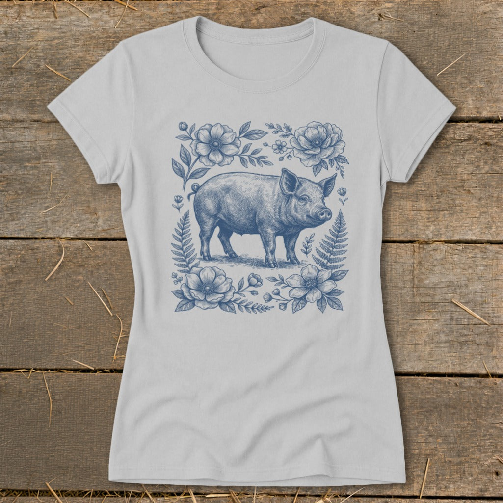Light gray t-shirt with blue illustration of a pig surrounded by flowers and ferns.