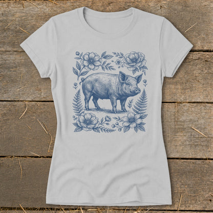 Light gray t-shirt with blue illustration of a pig surrounded by flowers and ferns.