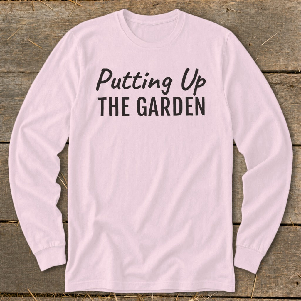Pink long-sleeve shirt with black text reading "Putting Up THE GARDEN".