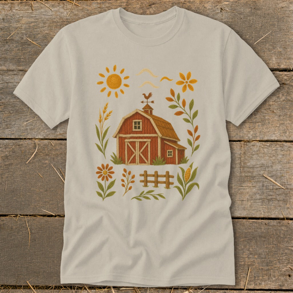 Cream t-shirt with embroidered barn, sun, and floral motif.