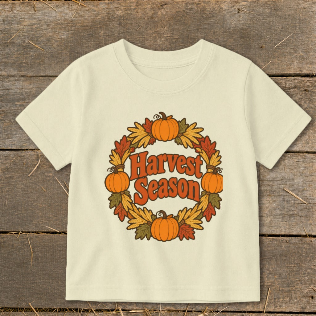 Cream t-shirt with "Harvest Season" text inside a pumpkin and leaf wreath.