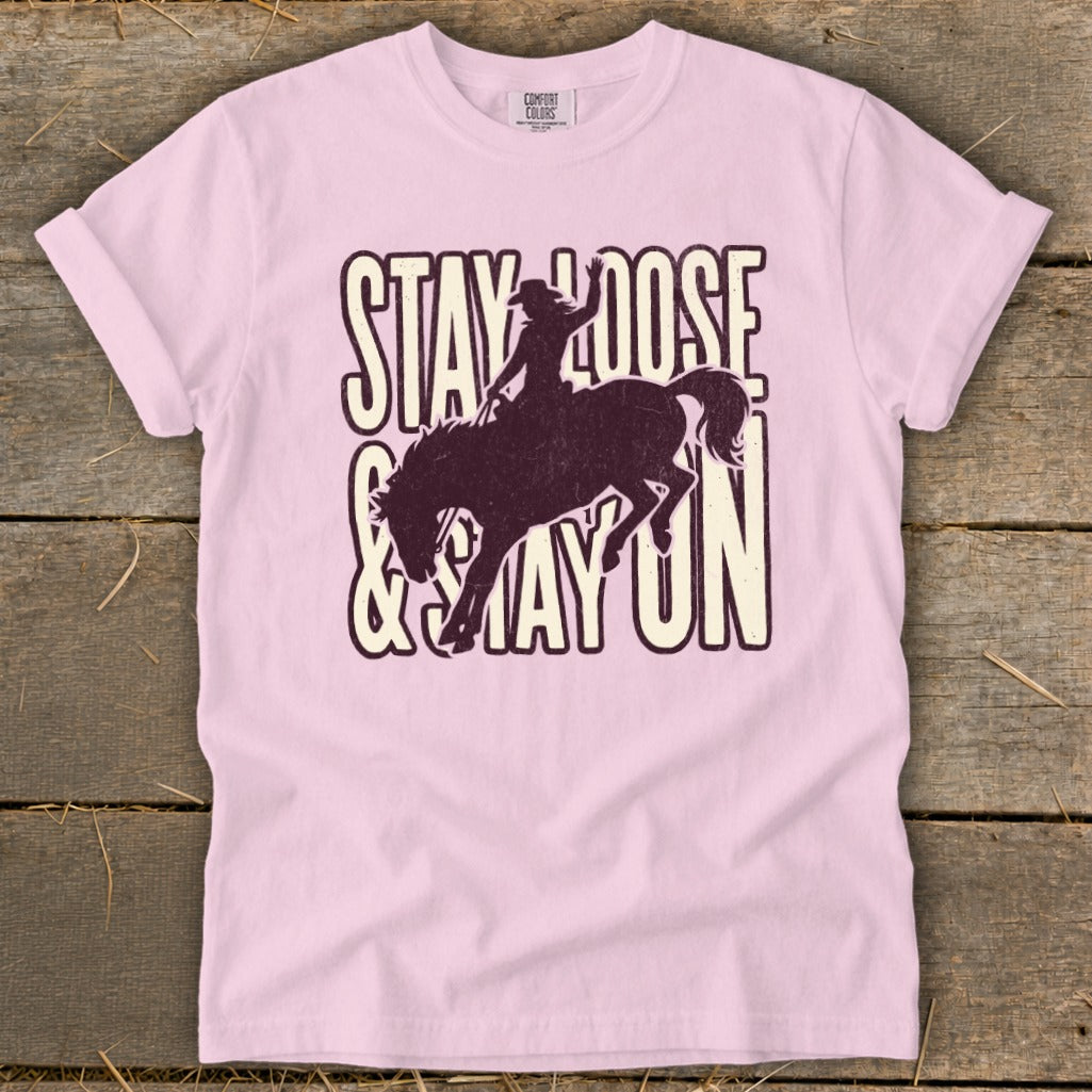 Pink t-shirt with "Stay Loose & Stay On" text and bucking horse graphic.