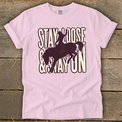 Pink t-shirt with "Stay Loose & Stay On" text and bucking horse graphic.