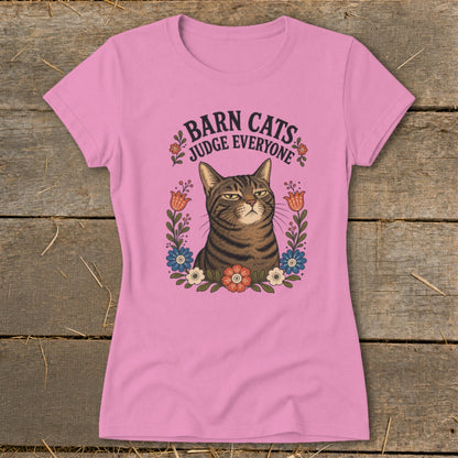 Pink t-shirt with a grumpy cat illustration surrounded by flowers and text that reads "Barn Cats Judge Everyone".