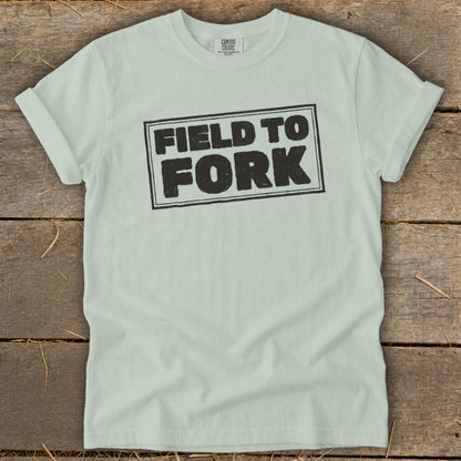 Sage green crewneck t-shirt featuring a black block-letter graphic that reads FIELD TO FORK.