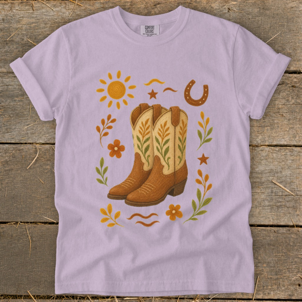 Purple t-shirt with cowboy boots, sun, horseshoe, flowers, and leaves design.