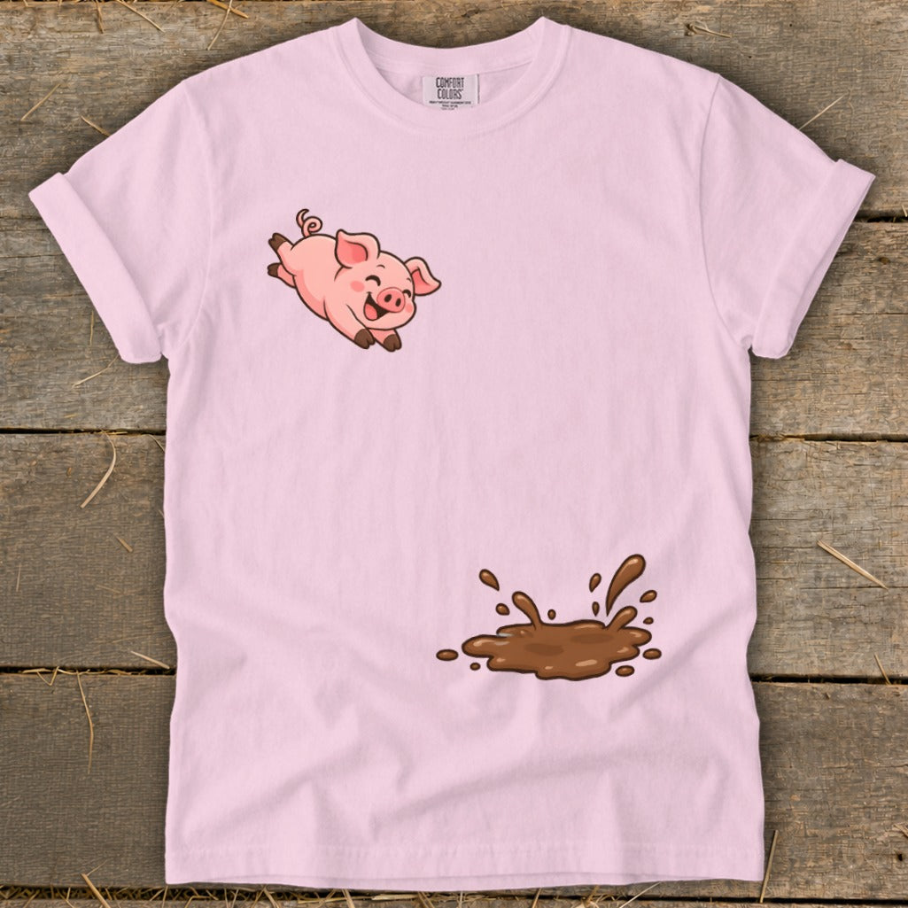 Pink t-shirt with a cartoon pig jumping above a mud splatter graphic.