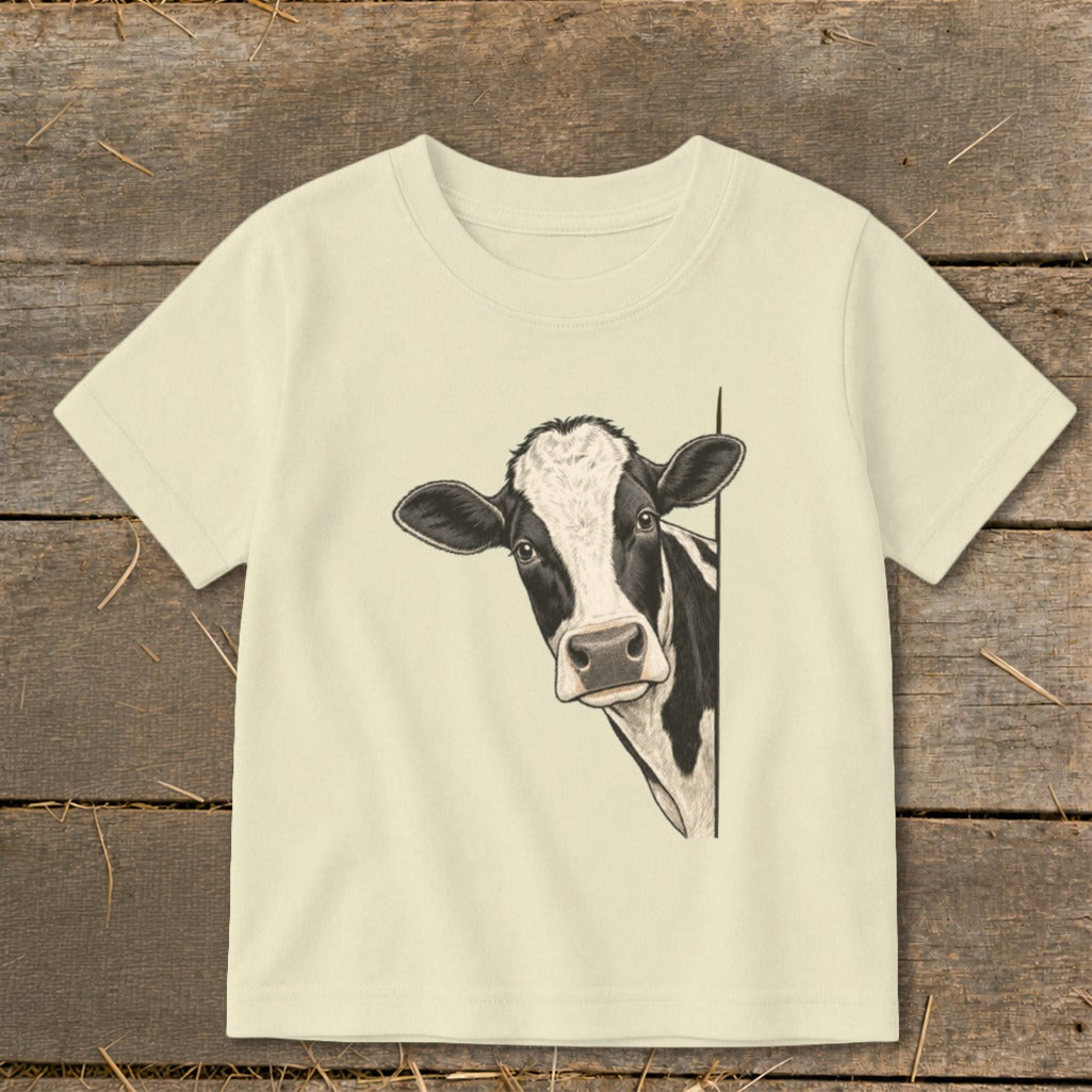 T-shirt with a black and white cow peeking around the side.