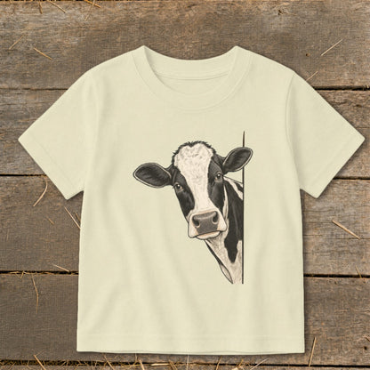 T-shirt with a black and white cow peeking around the side.