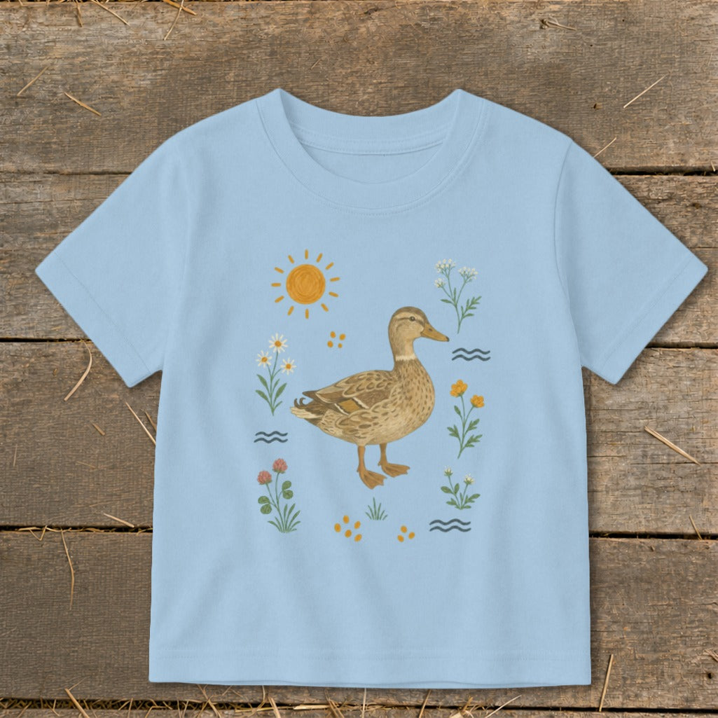 Light blue t-shirt with a mallard duck surrounded by flowers, sun, and waves.
