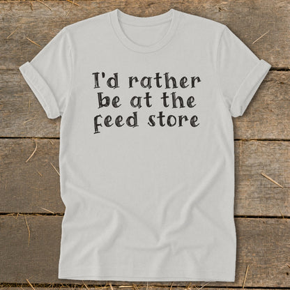 White t-shirt with black text reading "I'd rather be at the feed store."