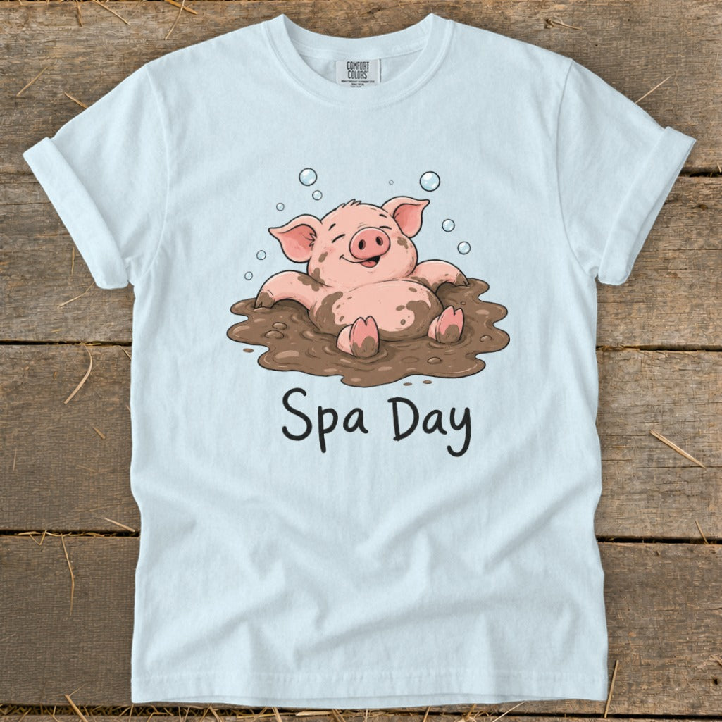White t-shirt with a cartoon pig relaxing in a mud bath, text reads "Spa Day".