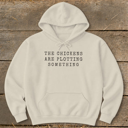 Cream hoodie with black text reading "THE CHICKENS ARE PLOTTING SOMETHING".