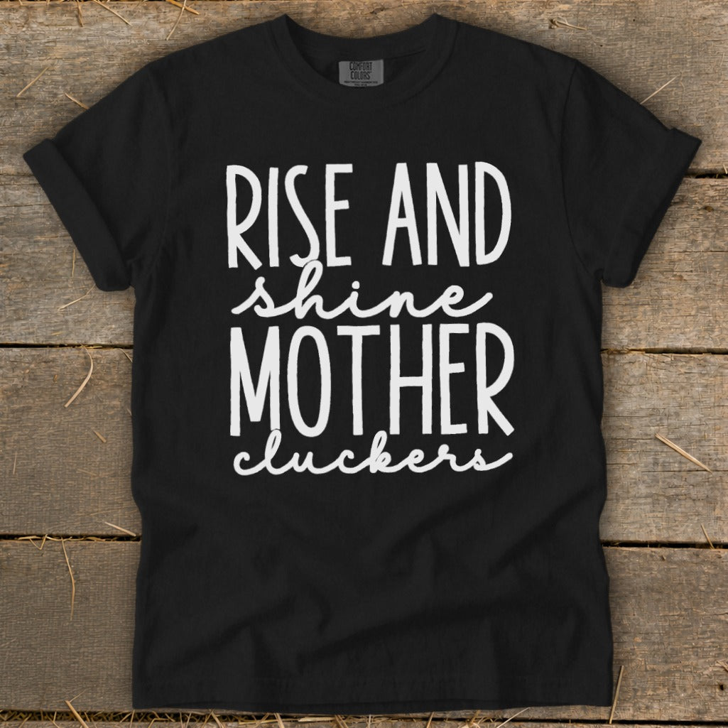 Black t-shirt with white text reading "Rise and shine mother cluckers".
