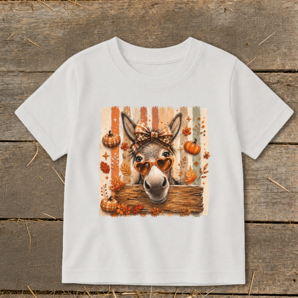 Donkey wearing heart sunglasses and plaid bow on a striped background with pumpkins and leaves.