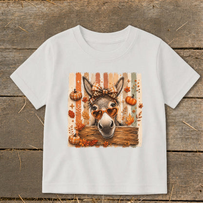 Donkey wearing heart sunglasses and plaid bow on a striped background with pumpkins and leaves.