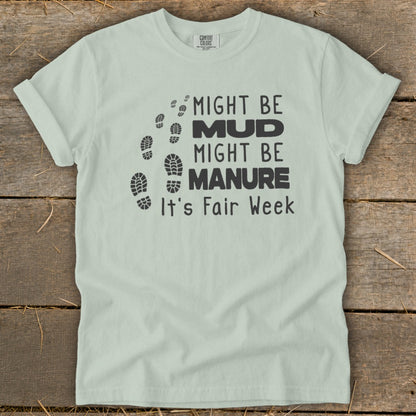 Light green t-shirt with black text and footprints: "Might be Mud, Might be Manure, It's Fair Week."