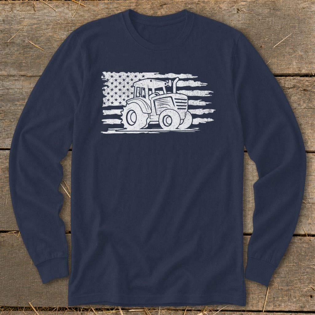Tractor silhouette over distressed American flag graphic on navy long-sleeve shirt.