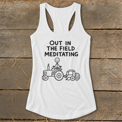 White tank top with "Out In The Field Meditating" text and stick figure on tractor.
